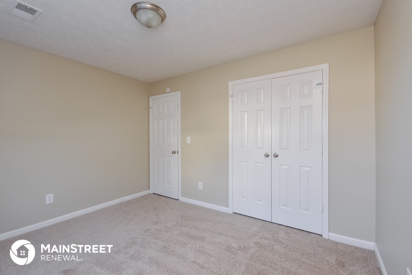 a bedroom with two closets and a carpeted floor