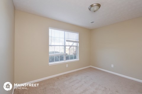 the spacious living room with a large window and beige carpet