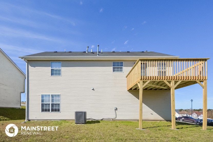 the back of a white house with a deck and a