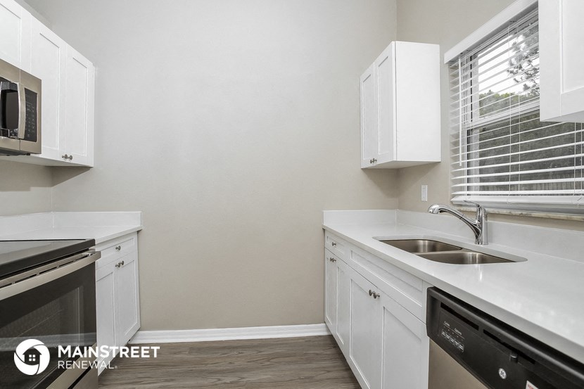 a kitchen with white cabinets and a sink and a window