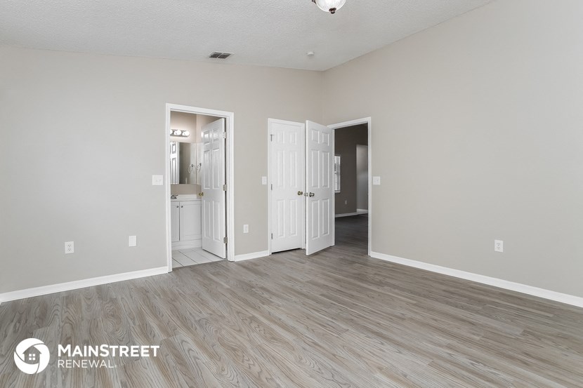 the living room of an apartment with white walls and wood flooring