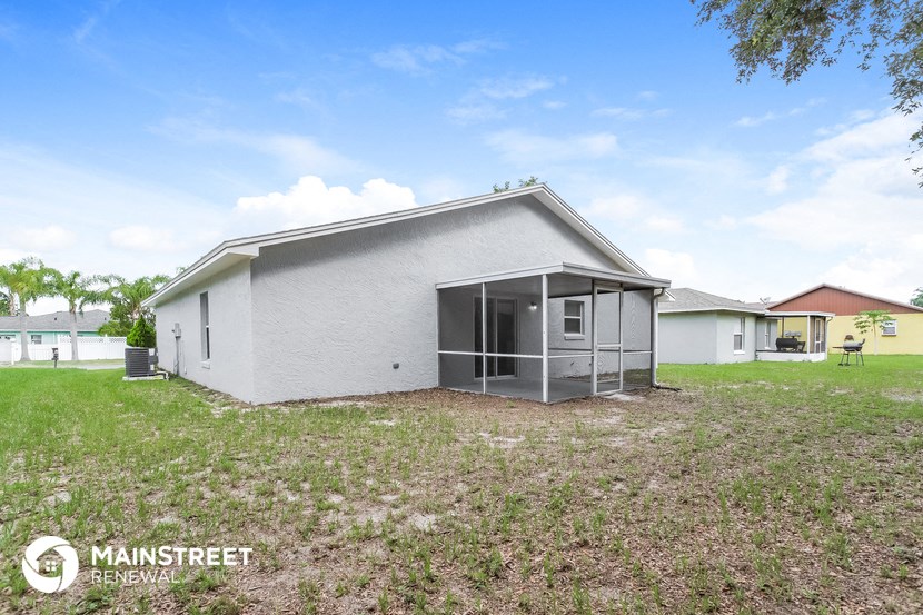 a small white house with a garage and a grass field