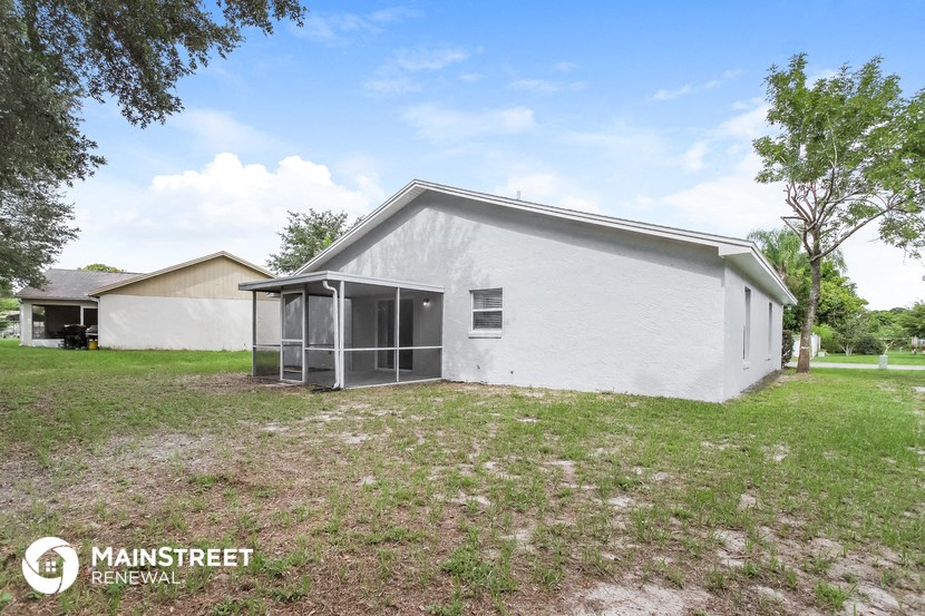 a small white house with a glass door and a grass field