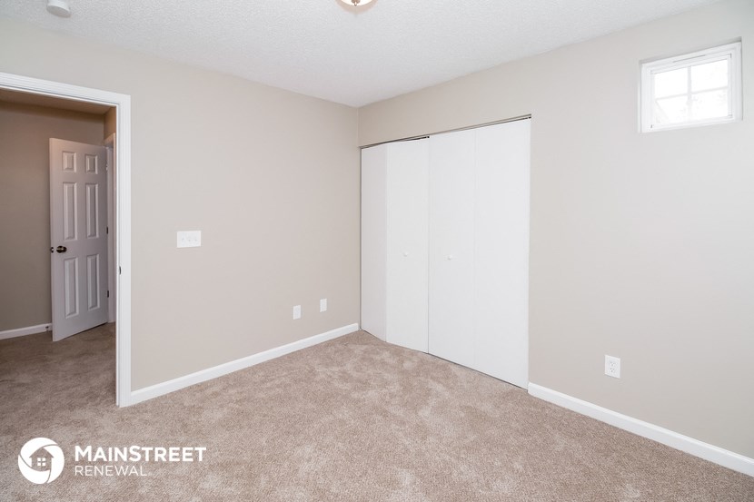 a bedroom with a door to a closet and a carpeted floor