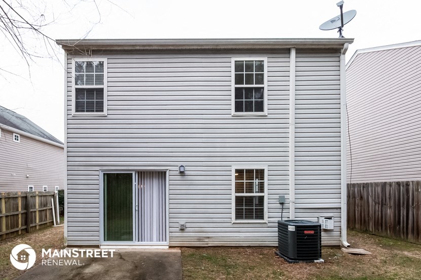 the exterior of a house with white siding and a trash can