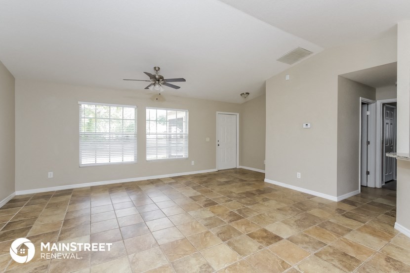 an empty living room with tile flooring and a ceiling fan
