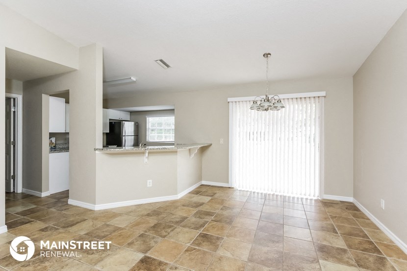an open kitchen and living room with tile flooring and a large window