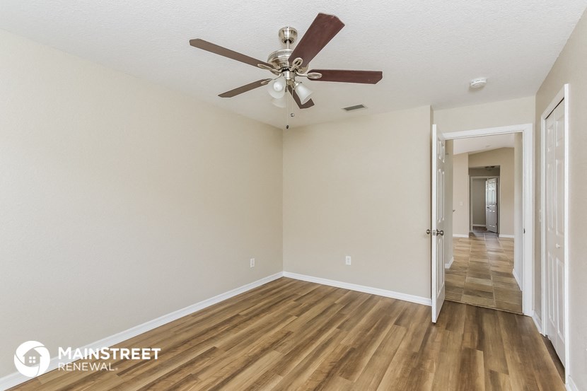the spacious living room with ceiling fan and hardwood flooring