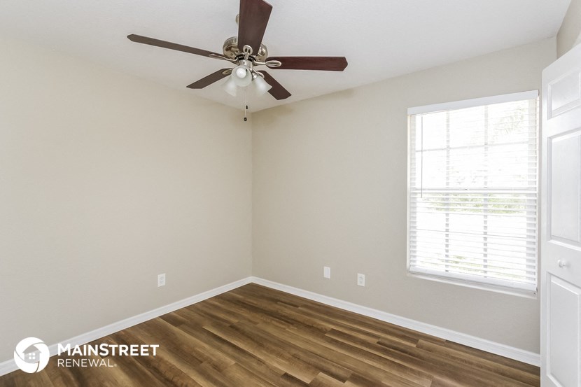 the interior of a bedroom with a ceiling fan and wood floors