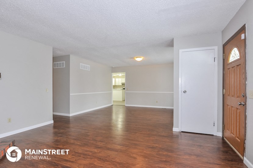 an empty living room with wood flooring and white walls