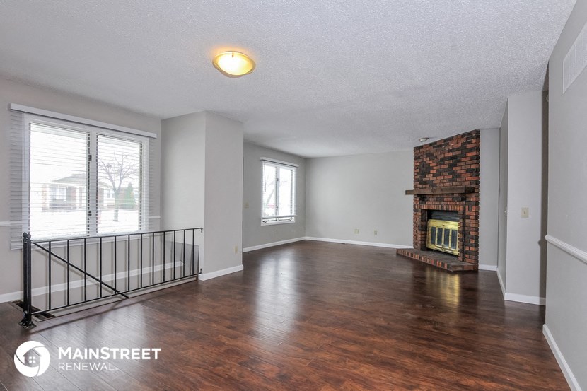 an empty living room with a fireplace and wood flooring