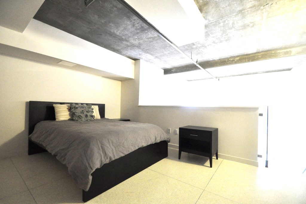 a bedroom with a bed and a concrete ceiling