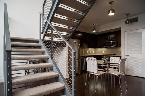 a stairwell leading up to a kitchen with a table and chairs