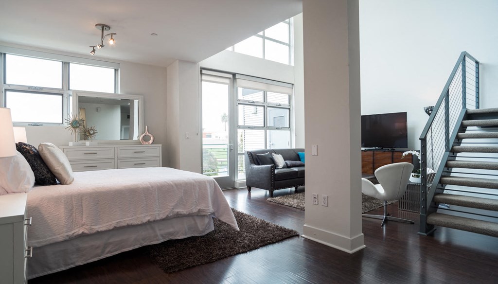 a bedroom with a bed and a staircase     and a living room