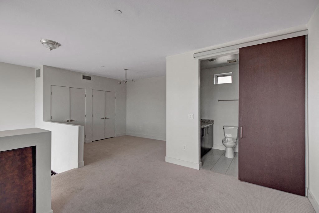 an empty living room with a door to a bathroom