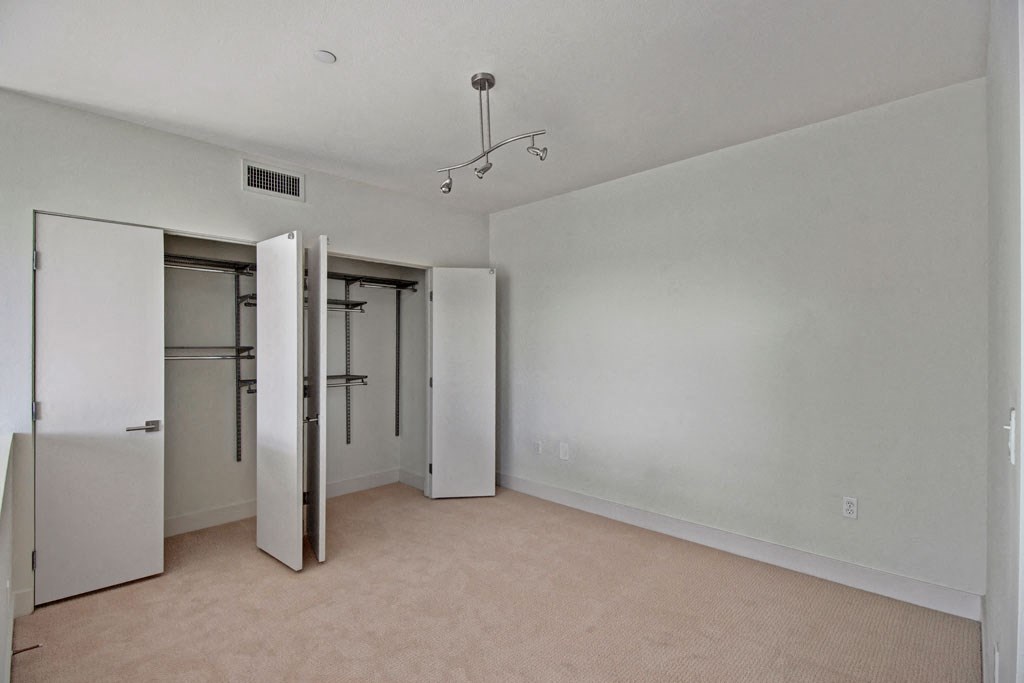 an empty room with a closet and mirrored doors