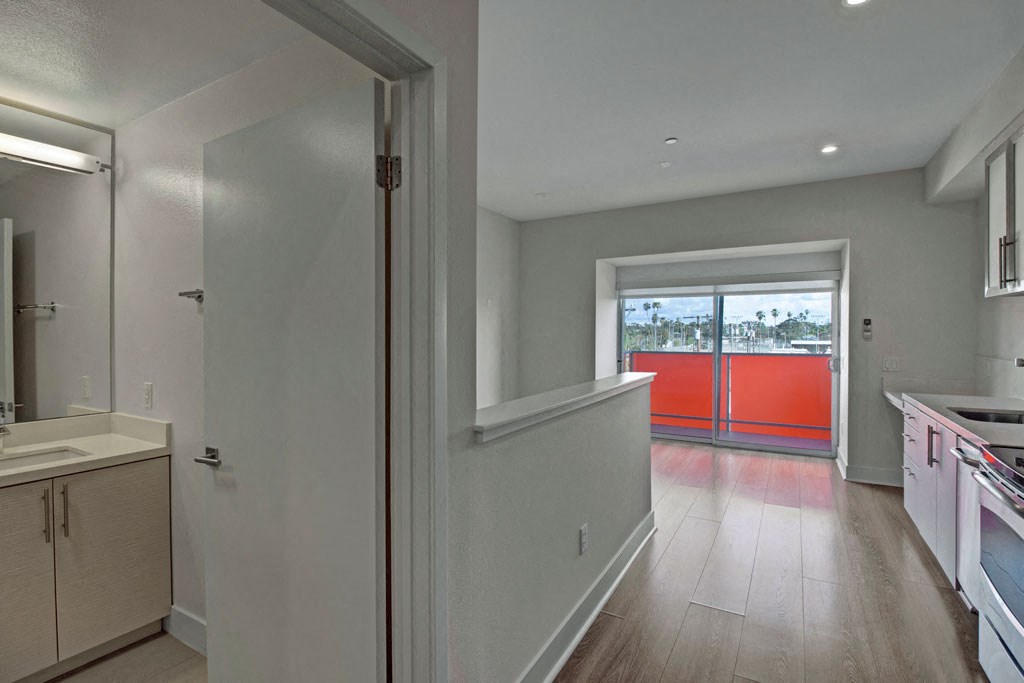 a kitchen and hallway with a door to a balcony