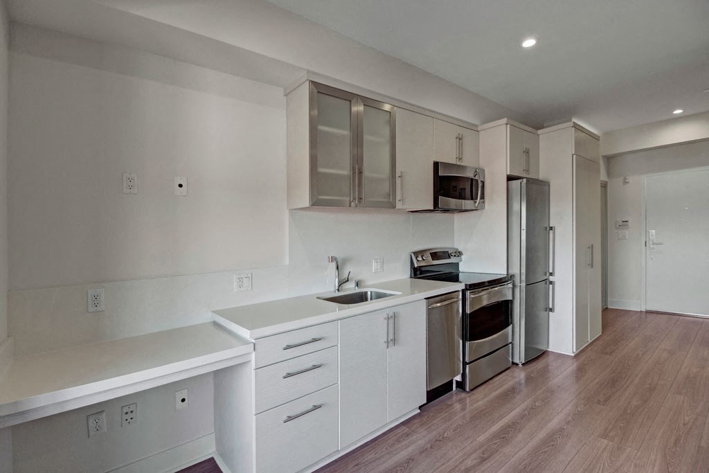 a kitchen with white cabinets and a sink and a refrigerator