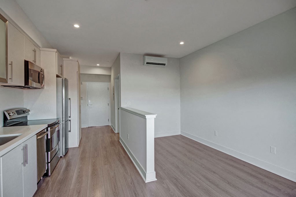 an empty kitchen and living room with white walls and wood flooring