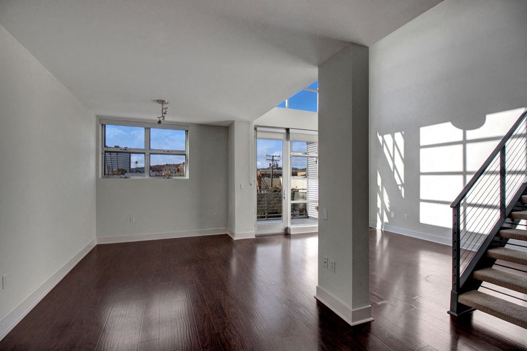 an empty living room with hardwood floors and a staircase