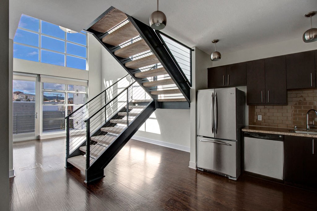 a kitchen with a stainless steel refrigerator next to a staircase