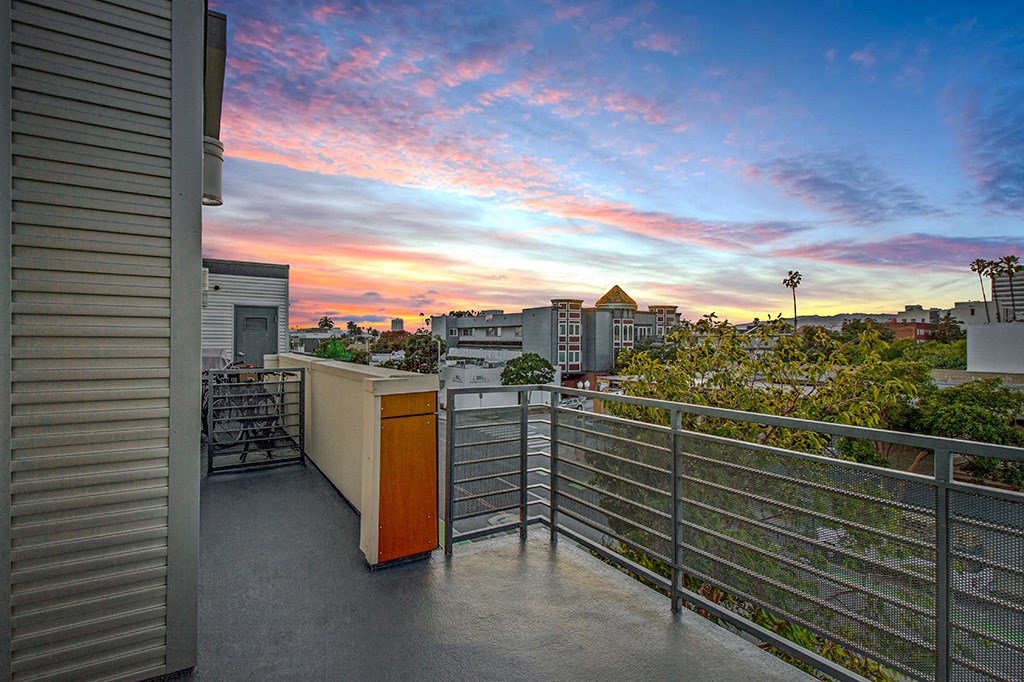 a balcony with a view of a city at sunset
