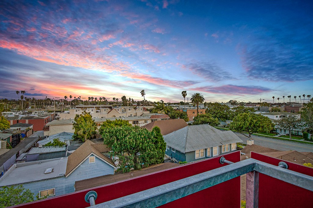 a view of the rooftops of houses in a city at sunset