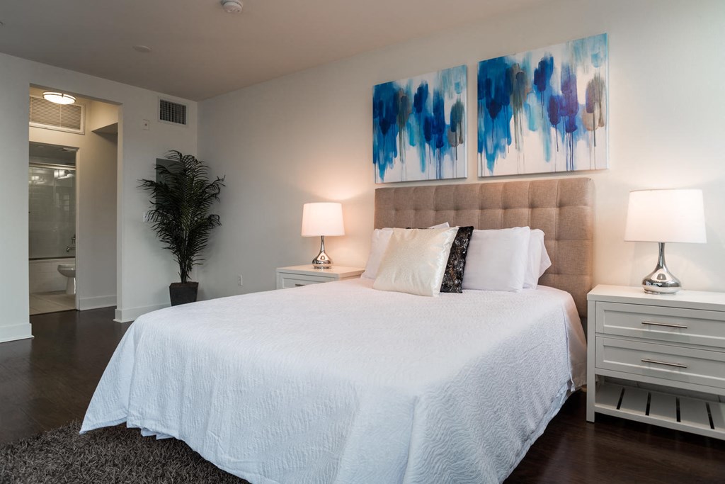 a bedroom with a large bed and paintings on the wall