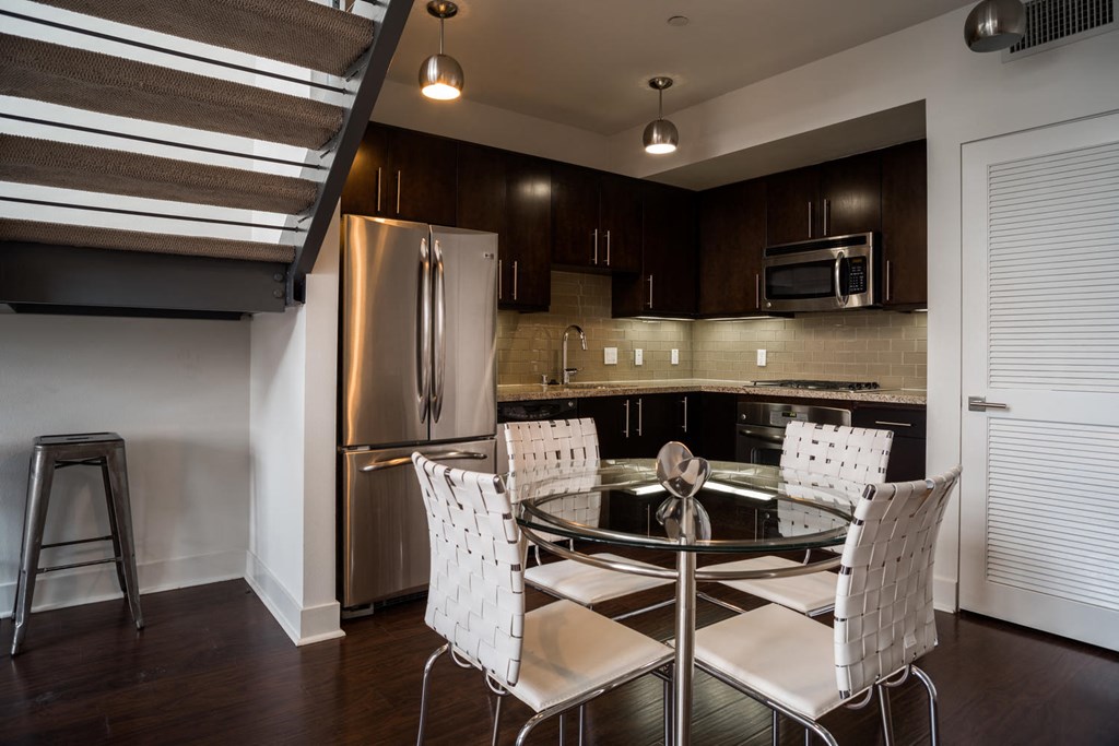 kitchen with stainless steel appliances and a glass table with white chairs
