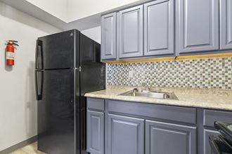 a kitchen with blue cabinets and a black refrigerator