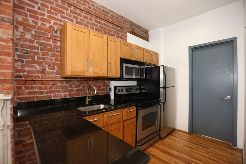 a kitchen with black appliances and a brick wall
