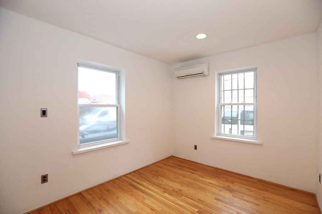 an empty room with a wood floor and two windows
