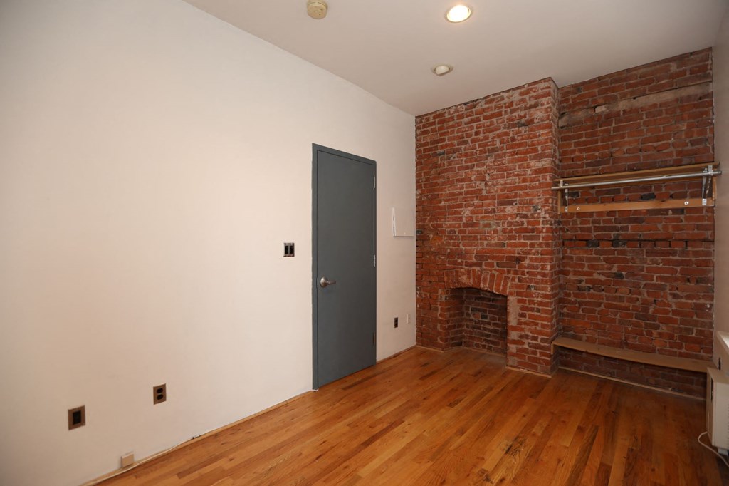 an empty room with a brick wall and a door
