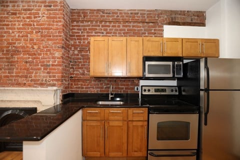 a kitchen with a brick wall and wooden cabinets