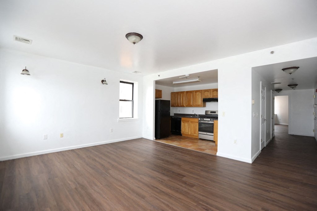 an empty living room and kitchen with white walls and wood floors