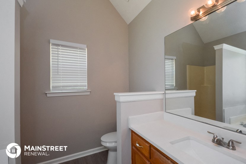 the bathroom has a large mirror and a sink and a toilet