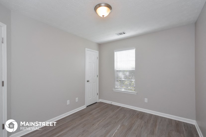 the spacious living room with white walls and wood flooring