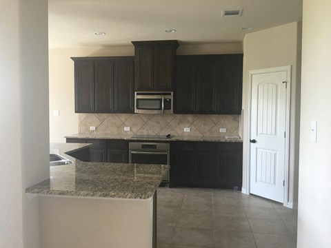 an empty kitchen with black cabinets and a counter top