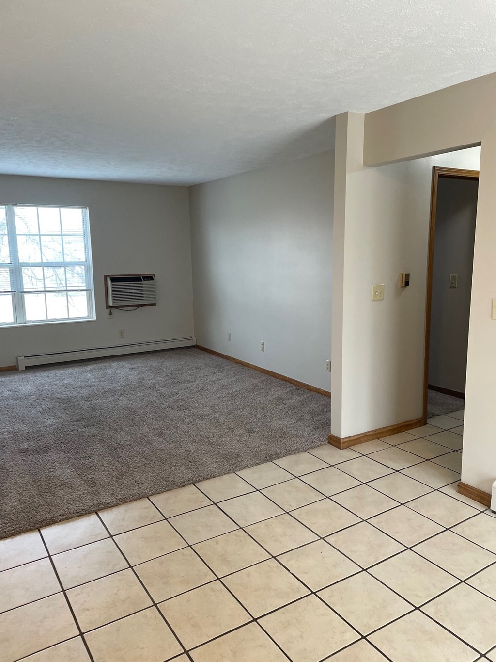 an empty living room with a tiled floor and a window