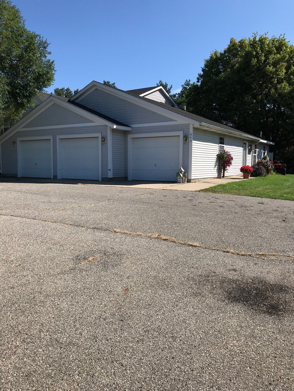 a white house with white garage doors and a gravel driveway