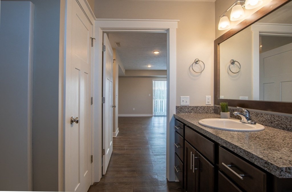 a bathroom with a sink and a mirror and a hallway