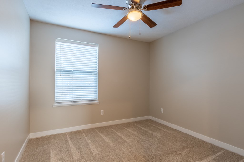 an empty room with a ceiling fan and a window