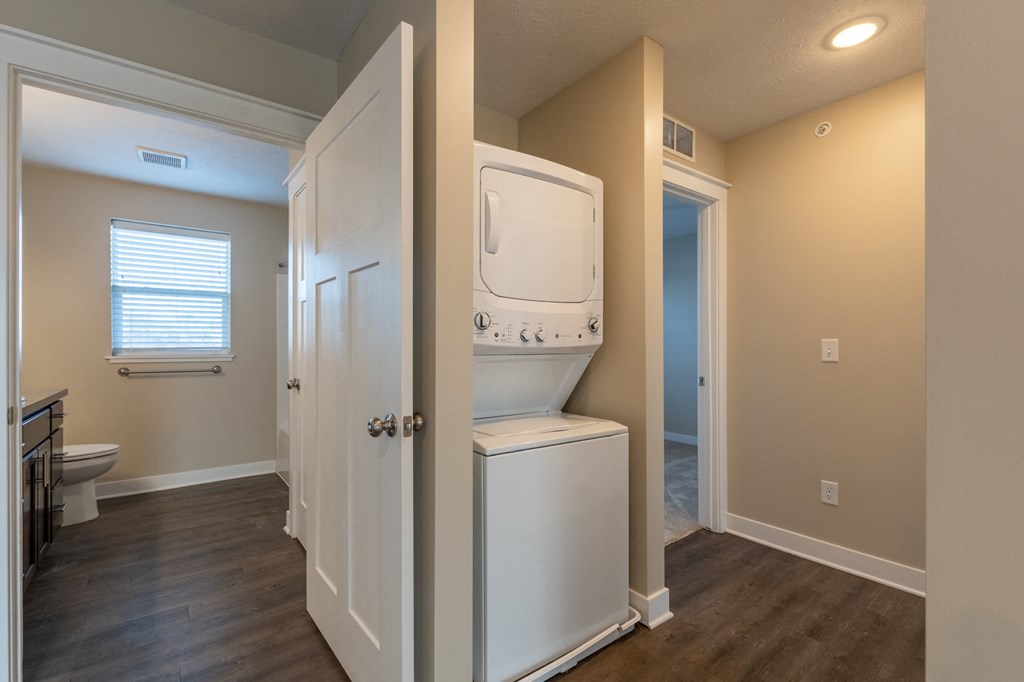 a laundry room with a washer and dryer on the wall and a toilet