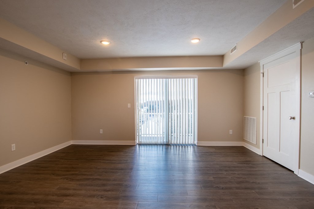 an empty living room with wood floors and a sliding glass door