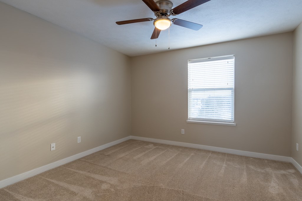 an empty room with a ceiling fan and a window
