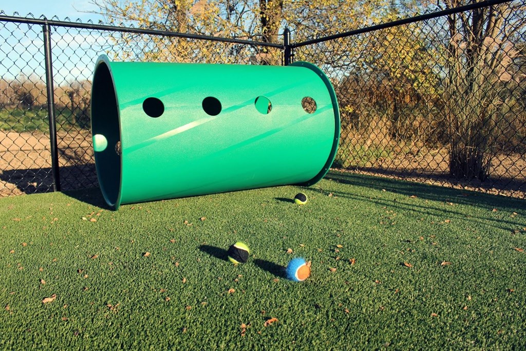 a green tube with a bowling ball in the grass