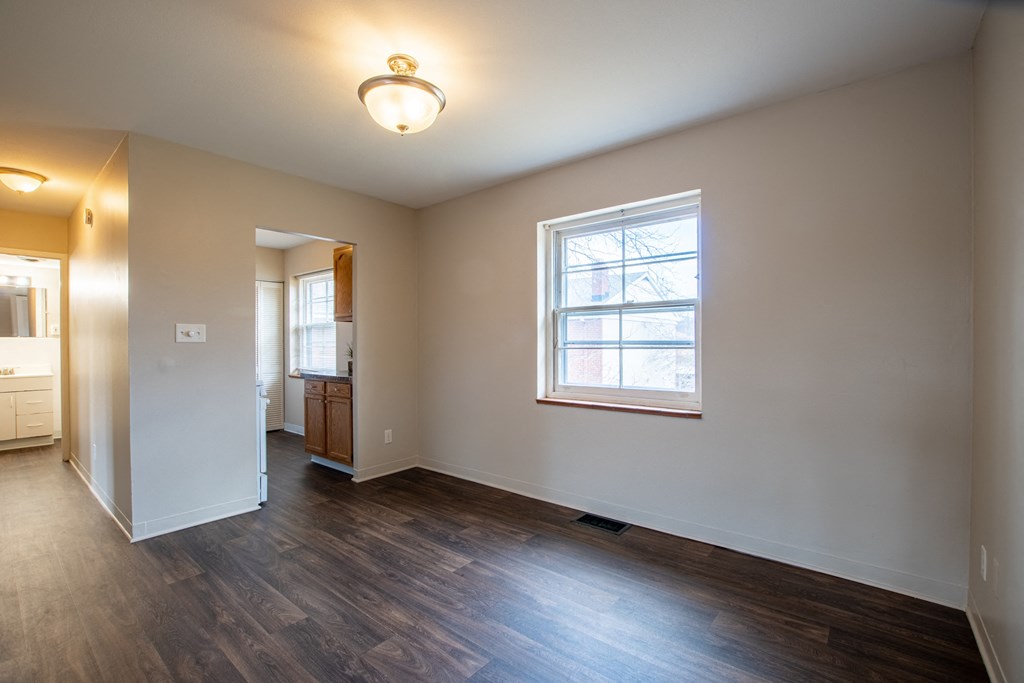 an empty living room with wood floors and a window