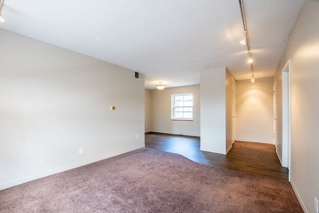 a empty living room with white walls and a window