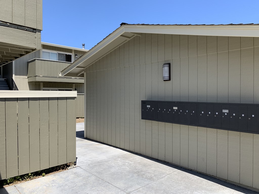 a gray garage with a black fence and a blue sky