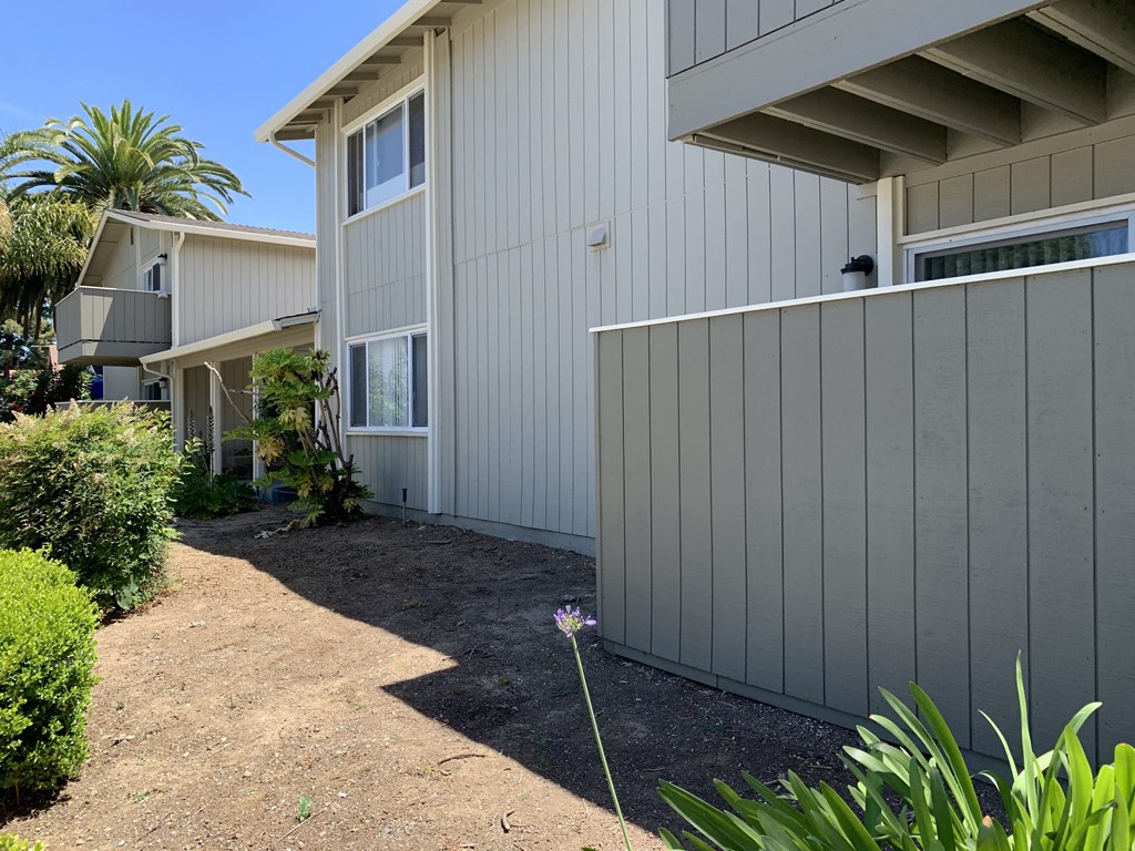 a side view of a house with a gravel pathway and a fence